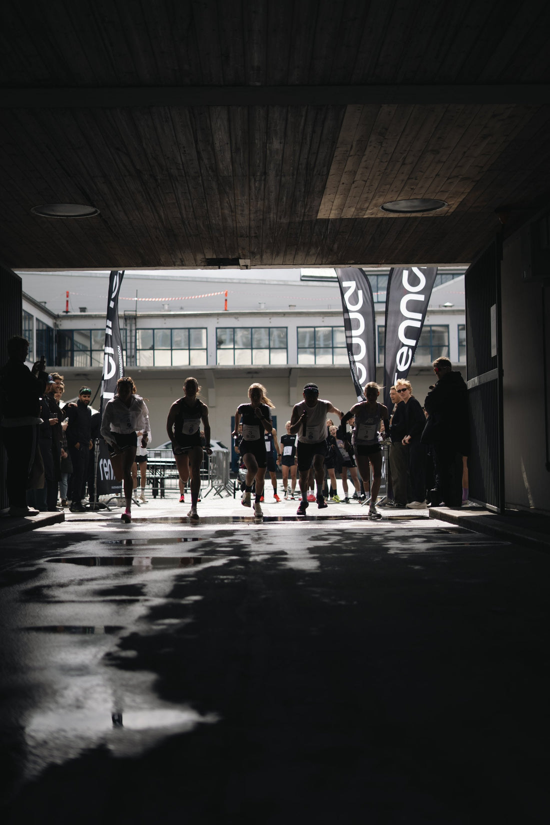 Battle of the Communities Vol.01 relay race, Kodbyen Copenhagen, wet street reflections under the Renna arch